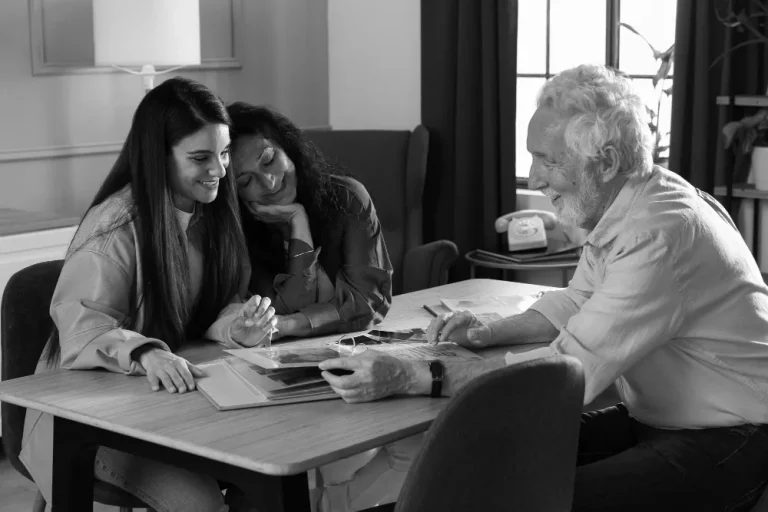 Three people sit at a table, engaged and smiling as they review documents related to an irrevocable life insurance trust.