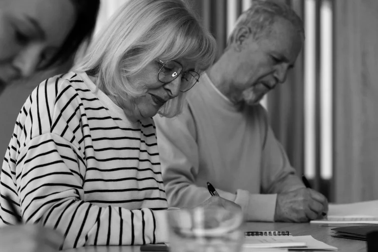 A group of older adults attentively taking notes, possibly learning about mega backdoor Roth strategies.
