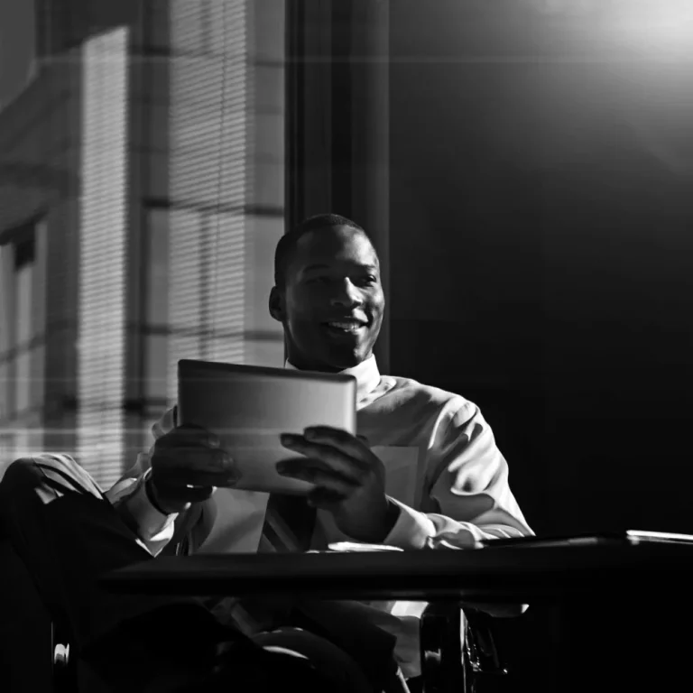 A person in a business setting smiles while reviewing documents on a tablet, with sunlight streaming through large windows, symbolizing understanding of QBI deduction.