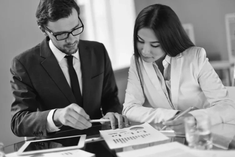 A financial advisor and a client review documents and charts together during a consultation, emphasizing the importance of asking informed questions.
