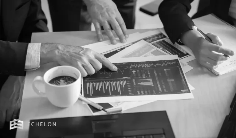 Professionals analyze financial charts and documents on a wooden table, illustrating the analytical nature of a hedge fund environment.