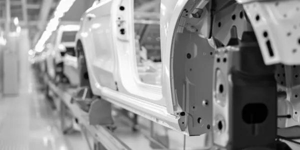 Car bodies on an assembly line in a factory setting, focusing on the metal frame of a vehicle.