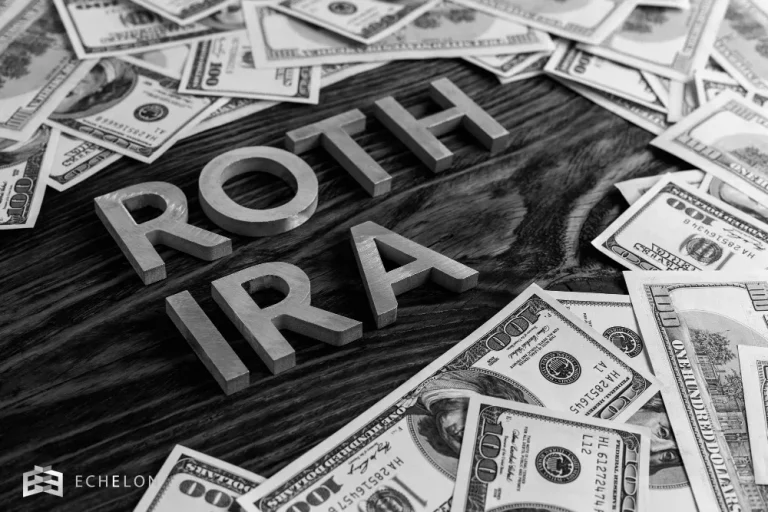The words "ROTH IRA" are displayed prominently on a wooden surface surrounded by numerous scattered $100 bills, symbolizing the concept of a Roth IRA conversion.