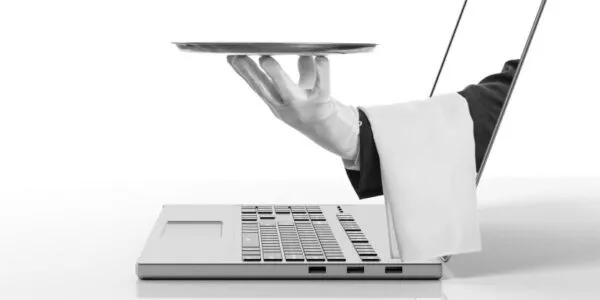 A gloved hand holding a tray emerges from a laptop screen, resembling a digital waiter.