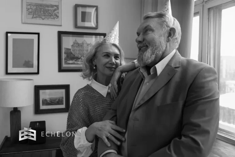 An elderly couple wearing party hats shares a joyful moment in their living room, symbolizing the celebration of successful retirement tax planning.