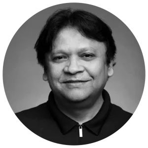 Black and white portrait of a person with medium-length hair, smiling slightly, wearing a dark collared shirt.