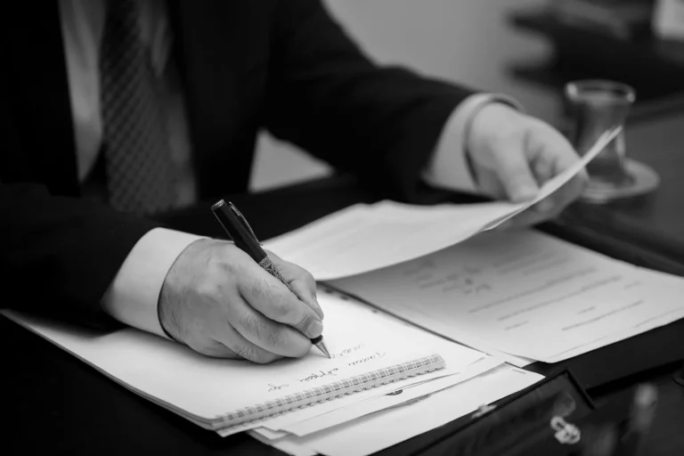 A person in a suit is signing legal documents related to a durable power of attorney at a desk.