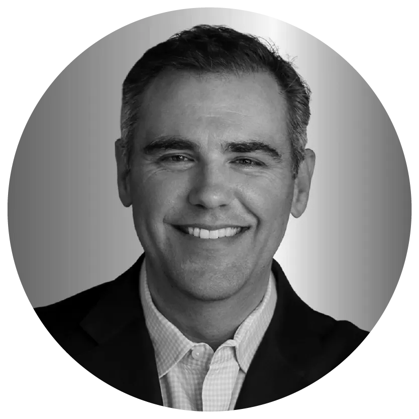 Smiling man in a suit and collared shirt in a grayscale circular frame.