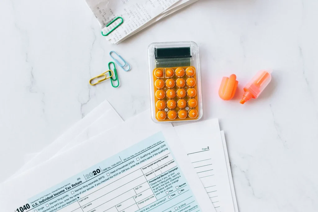 Tax preparation setup for high net worth wealth management in Austin, featuring IRS tax forms, a calculator, receipts, paper clips, and a highlighter on a marble surface.