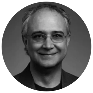 Smiling man with glasses and short gray hair, wearing a dark suit, in a black and white circular-cropped portrait.